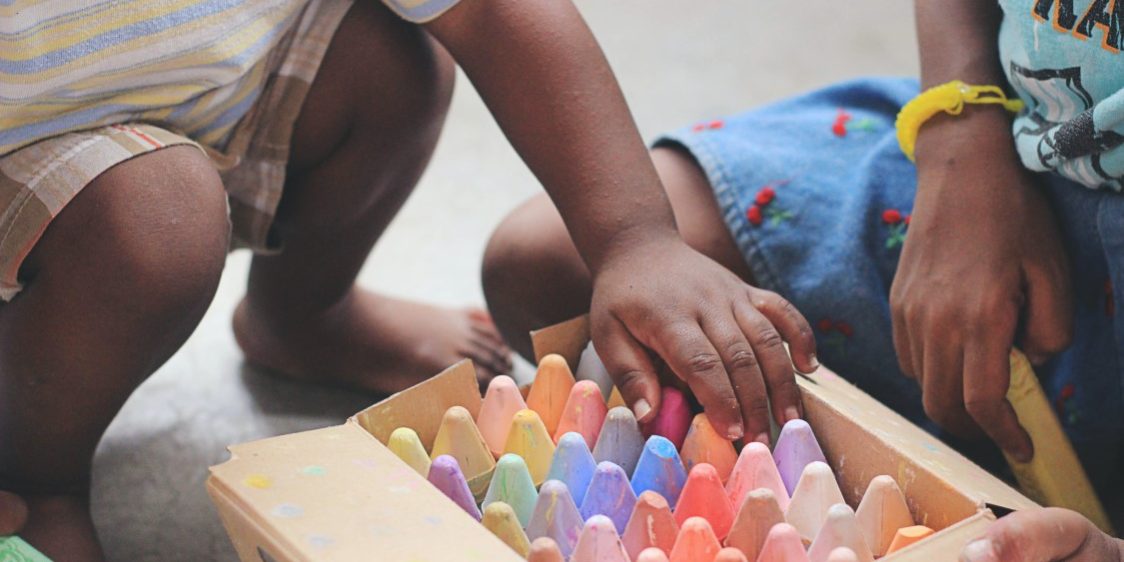 Young children unpacking a box of brightly coloured chalk.