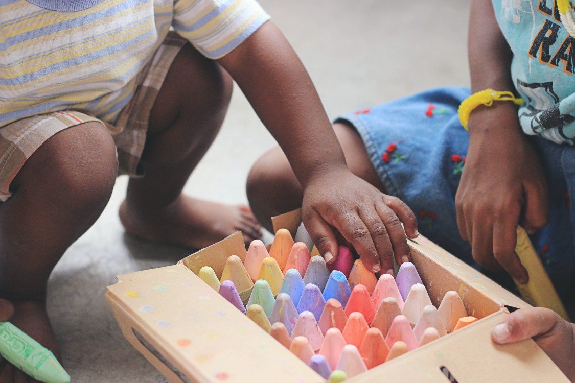 Young children unpacking a box of brightly coloured chalk.